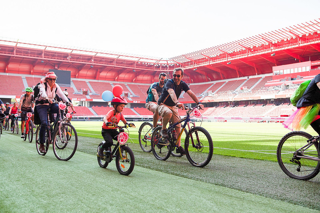Famille et cyclistes Vélotour traversent la pelouse d'un stade